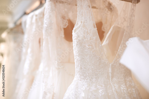 Fotografie Close Up Of Beautiful Bridal Wedding Dresses Hanging On Rail In Shop