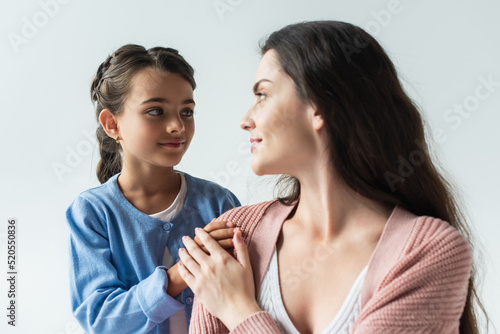 girl touching shoulder of blurred mother isolated on grey