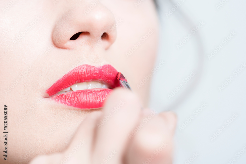 Naklejka premium Makeup. Makeup Artist Hand Brush on Lipstick.
