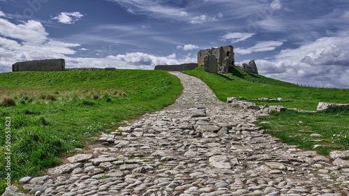 Stone path through green valley leads to ruins of Duffus Castle, located on grassy hill near Moray photo