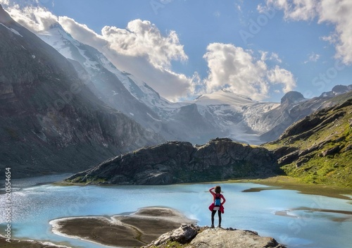 Person standing on a rock near Sandersee river and Grossglockner mountain in Austria photo