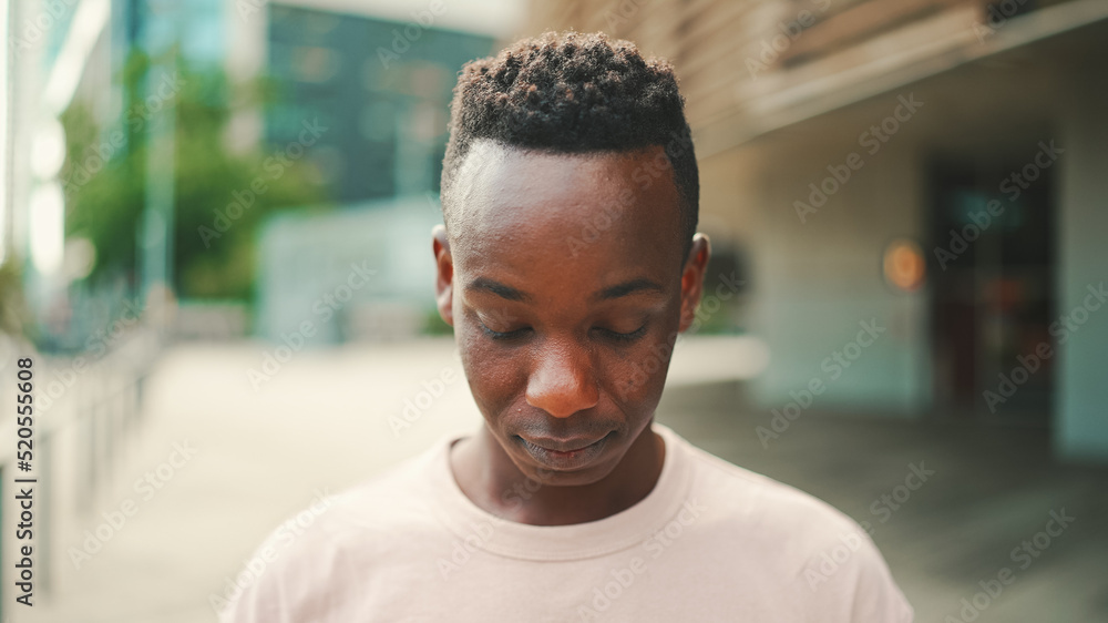Clouse up, young african student stands outside of the university, raises his head Clouse up, young african student stands outside of the university, raises his head