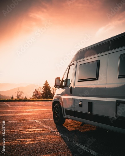 Fotografie, Tablou Campervan parked on the side of the road against a scenic sunset