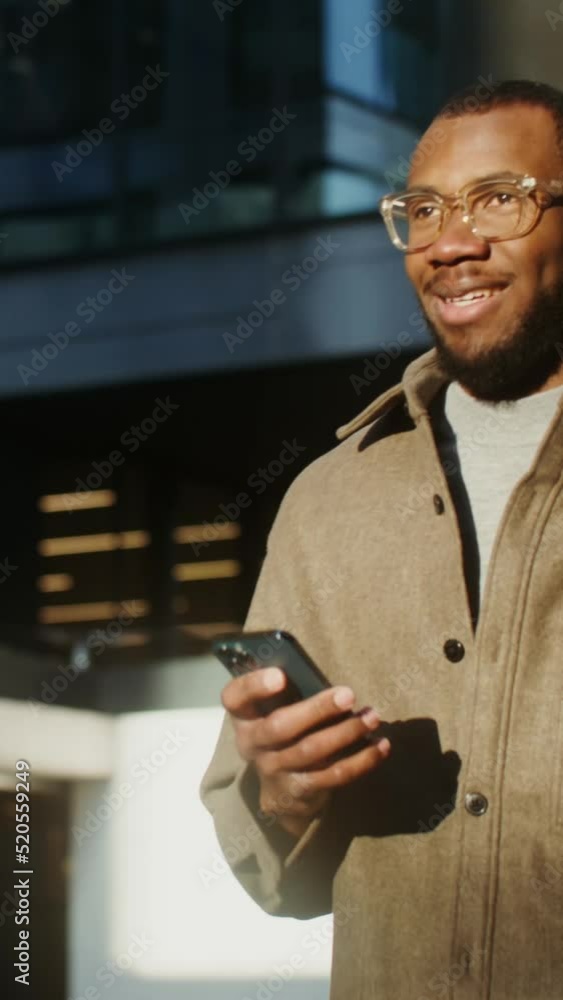 African-American man is typing on a mobile phone while walking in the city African-American man is typing on a mobile phone while walking in the city
