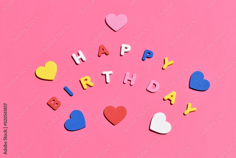 Happy birthday written with colorful letters and hearts on a light pink background. Birthday Card.