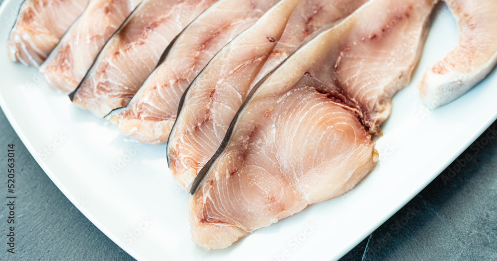 Close-up of various slices of raw swordfish, in a white plate, on a slate table..Tasty food from Italian cuisine and from the Mediterranean sea. Concept for a tasty and healthy meal. Close-up of various slices of raw swordfish, in a white plate, on a slate table..Tasty food from Italian cuisine and from the Mediterranean sea. Concept for a tasty and healthy meal.