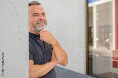 Thoughtful man leaning against a wall with a quiet smile