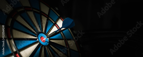 A dart hitting the center of target with copy space in dramatic light and shadow. Bullseye target or a dart dashboard for financial business planning and targeting with winner goal concept photo