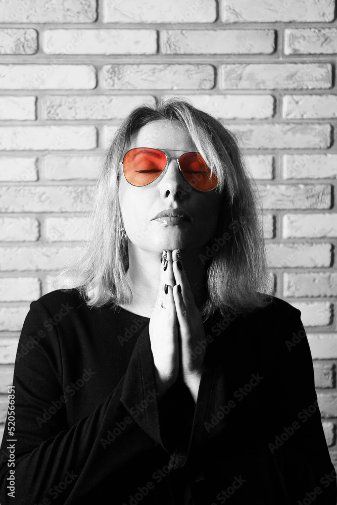The woman looks through rose-colored glasses. Black and white photo with an emphasis on pink glasses. The woman looks through rose-colored glasses. Black and white photo with an emphasis on pink glasses.
