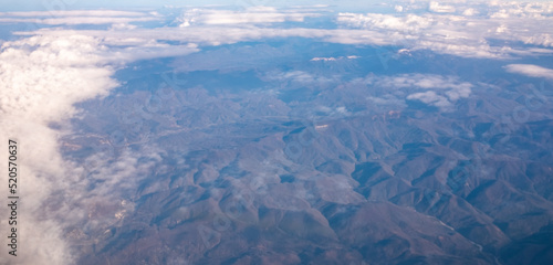 a bird's-eye view of the mountains and clouds in the sky from an airplane window