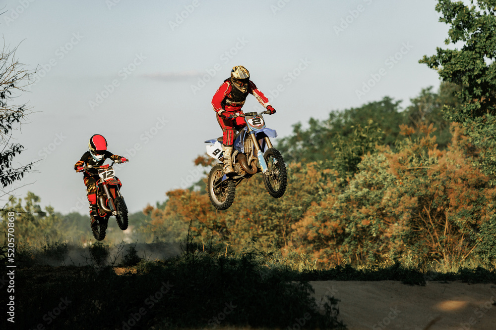Live shot of junior sportsman, motorcyclist training on motorbike at hot summer day, outdoors. Motocross rider in action. Motocross sport, challenges Live shot of junior sportsman, motorcyclist training on motorbike at hot summer day, outdoors. Motocross rider in action. Motocross sport, challenges