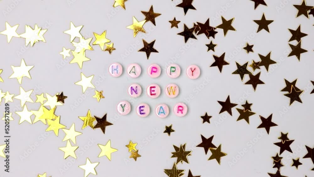 Happy New Year. Quote made of white round beads with colorful letters and golden confetti. Happy New Year. Quote made of white round beads with colorful letters and golden confetti.