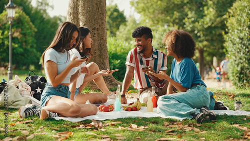 Close-up of young man with curly hair wearing striped shirt sitting in park having picnic on summer day outdoors, talking with friends