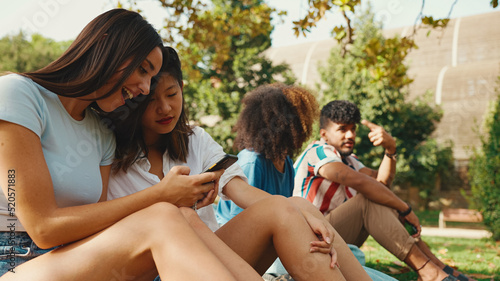 Happy, smiling multiethnic young people at picnic on summer day outdoors. Group of friends talking, using cellphone while relaxing in the park at picnic © Andrii Nekrasov