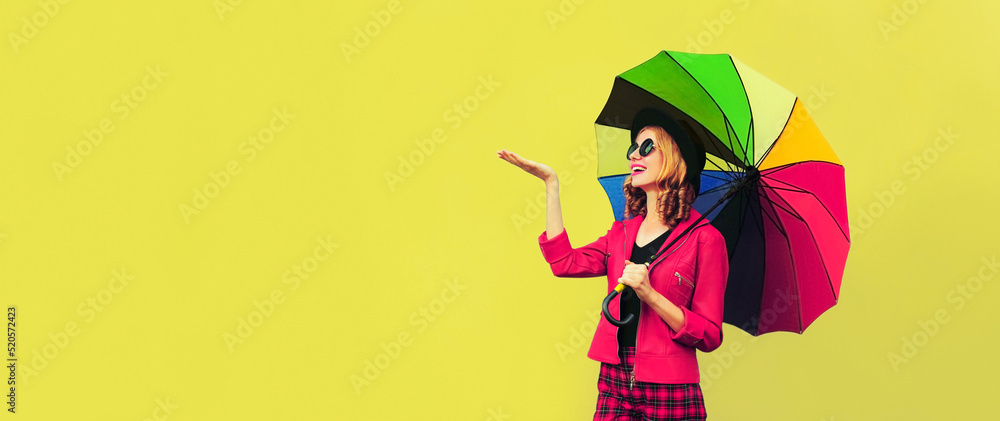Fototapeta premium Autumn portrait of happy smiling young woman holding colorful umbrella wearing jacket on background