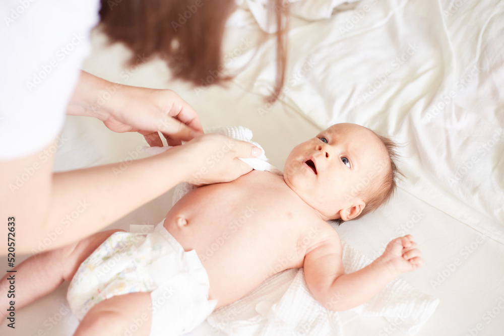 Mother dress her newborn baby boy. Realistic home portrait Mother dress her newborn baby boy. Realistic home portrait