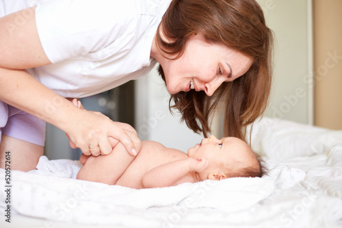 Mother Massaging Her newborn baby boy. Realistic home portrait