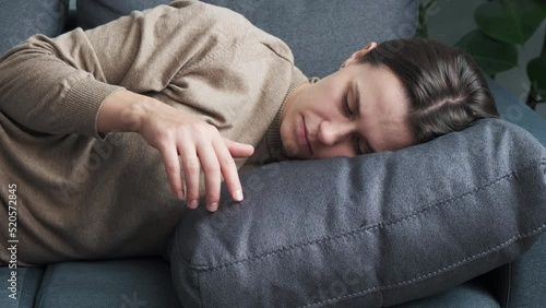 Close up of bored disinterested young female lying on grey sofa, suffering from loneliness alone at home, feeling unmotivated unproductive indoors, waste of time. Lazy inactive weekend pastime concept