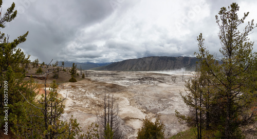Fototapeta Naklejka Na Ścianę i Meble -  Hot spring Geyser with colorful water in American Landscape. Cloudy Sky. Yellowstone National Park, Wyoming, United States. Nature Background Panorama
