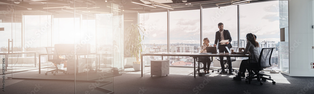 People standing near table, team of businessmen working and communicating together in modern office