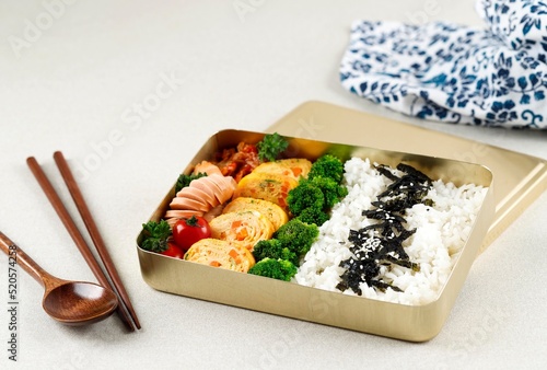 Korean Lunchbox Dosirak, Packed Meal Bento Lunchbox with various Banchan, Gyeran Mari, Tomato, Broccoli, Kimchi, and Sausage. photo