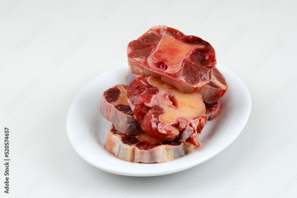 Raw Oxtail on WHite Plate, White Table, Copy Space for Text Raw Oxtail on WHite Plate, White Table, Copy Space for Text