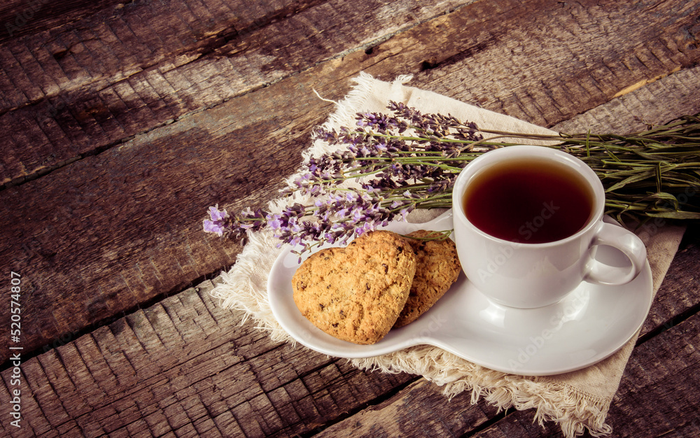 Cup of tea with lavender and cookies on a wooden table.
