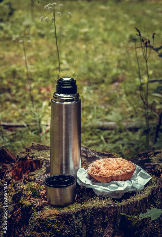 Camping tea in the forest. Thermos of tea on a stump
