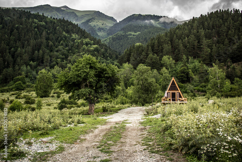 Obraz na płótnie House in the mountain forest. A frame house in a mountain valley w salonie