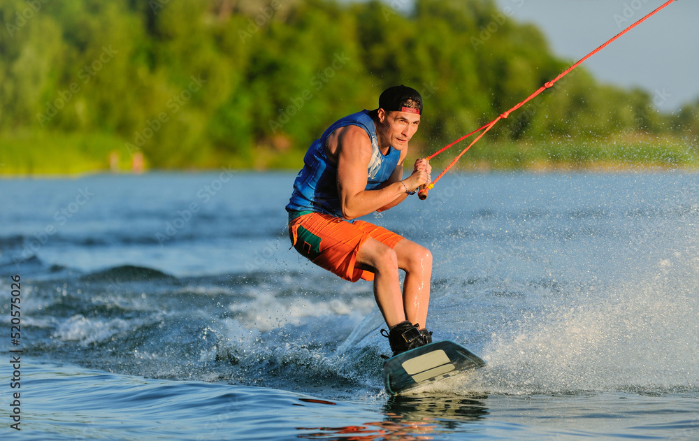 Fototapeta premium A professional wakeboarder rides on the lake in sunny weather, performing figures