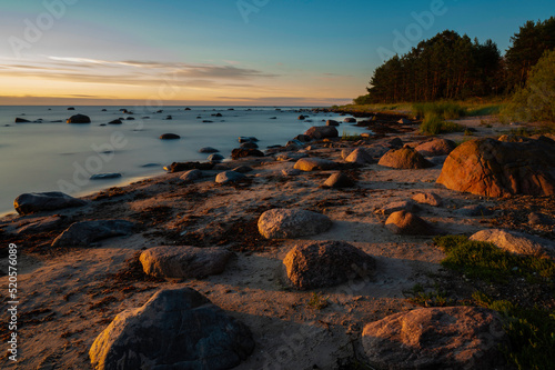 Sunrise on the beach with stones on coast.
