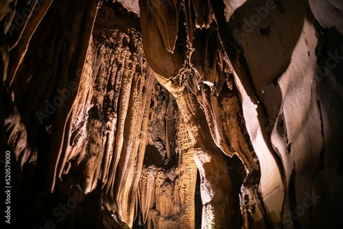 Low-angle view of long mineral stalactites hanging from the ceiling of the cave photo