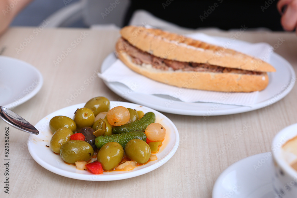 breakfast in open air summer cafe with tuna sandwich, cup of coffee, olives, cucumber and onion close up photo breakfast in open air summer cafe with tuna sandwich, cup of coffee, olives, cucumber and onion close up photo