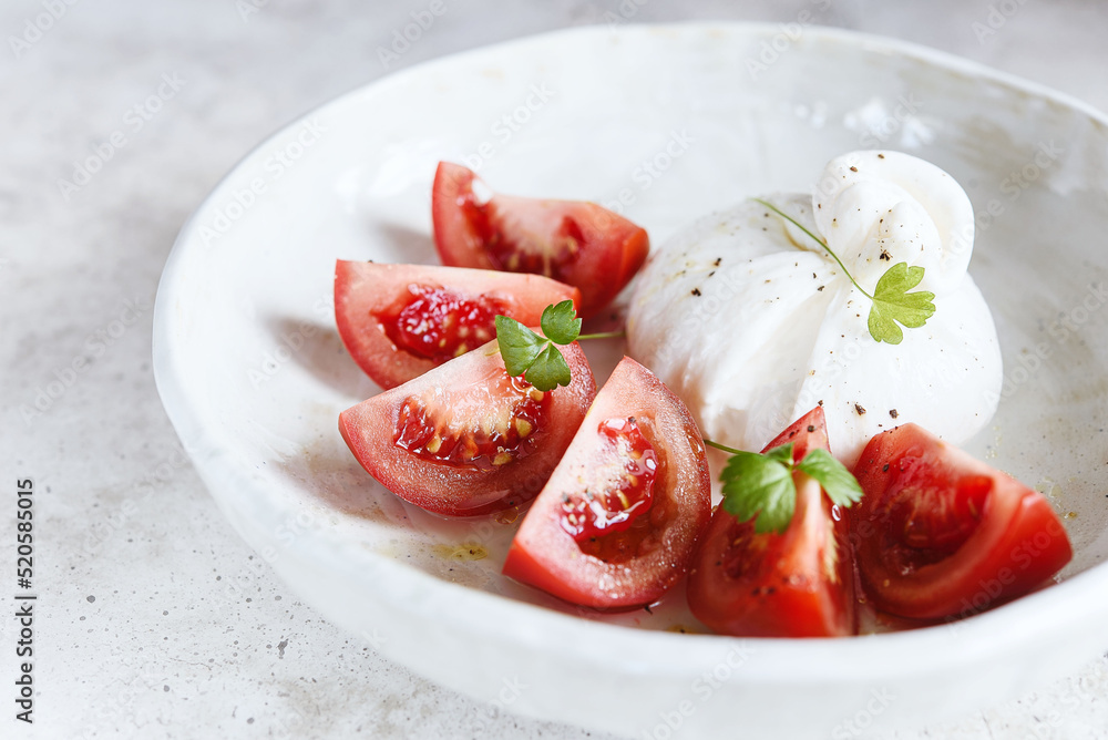 Italian burrata cheese with tomatoes and olive oil. Light summer dinner or snack. Healthy eating. Vegetarian food. Selective focus Italian burrata cheese with tomatoes and olive oil. Light summer dinner or snack. Healthy eating. Vegetarian food. Selective focus