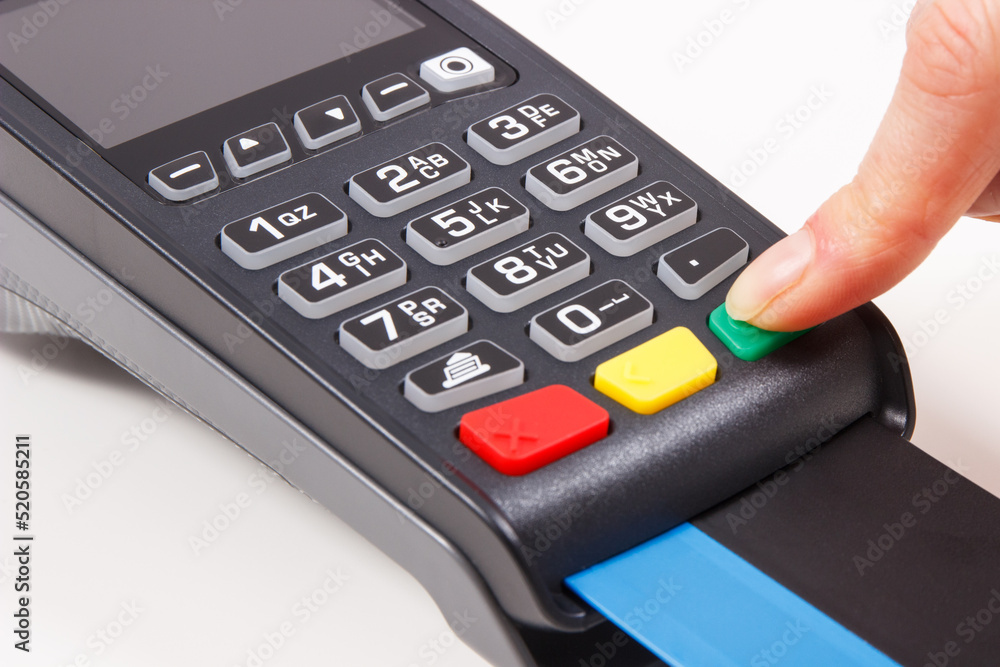 Hand of woman entering PIN code on payment terminal. Cashless paying for shopping. Finance concept