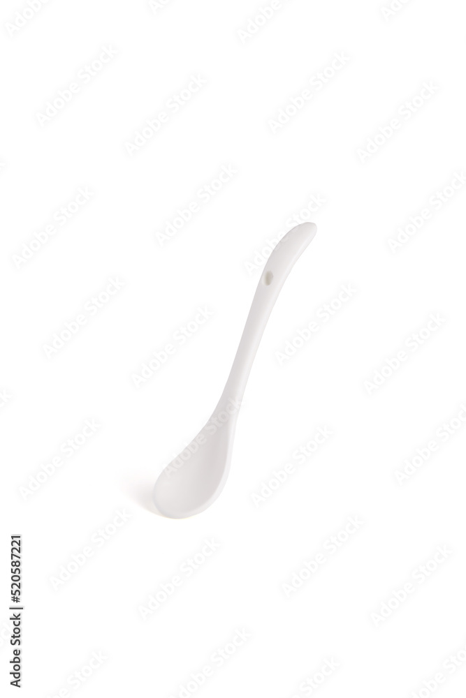 Close-up shot of a white ceramic spoon for products. The white ceramic mini spoon is isolated on a white background. Front view. Close-up shot of a white ceramic spoon for products. The white ceramic mini spoon is isolated on a white background. Front view.