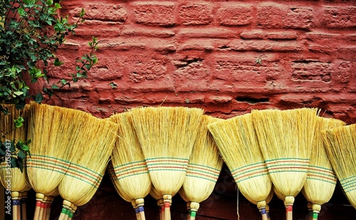 Collection of brooms leaning on the brick wall photo