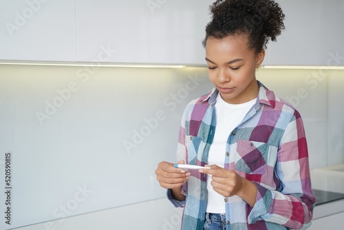 Pregnancy checking home test. Satisfied african american teenage girl gets pregnancy test result. photo