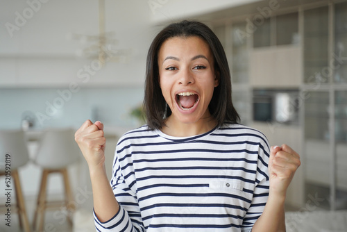 Excited happy woman makes yes gesture, celebrates relocation at new house, achievement, success