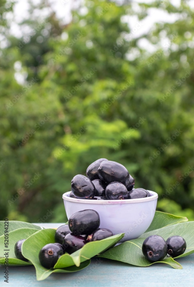Jamun or Syzygium Cumini in a Bowl with Leaves Isolated on Wooden