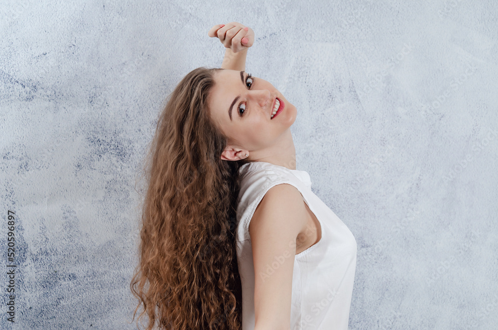 Portrait of a charming young woman. Long curly dark hair. She threw her head back. Dazzling smile. White blouse. Portrait of a charming young woman. Long curly dark hair. She threw her head back. Dazzling smile. White blouse.