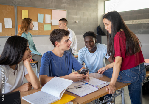 Group of multi-ethnic students talking in class during a break. High school, back to school, diverse students