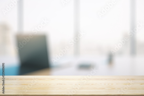 Empty wooden office table with light sunny workplace with computer on background, mock up