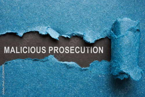 Words malicious prosecution on dark paper under blue one.