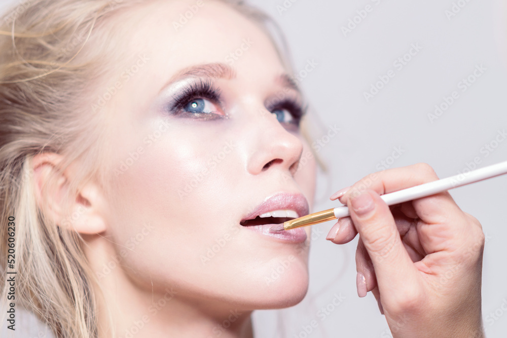 Makeup. Makeup artist hand brushes pink lipstick. Makeup. Makeup artist hand brushes pink lipstick.