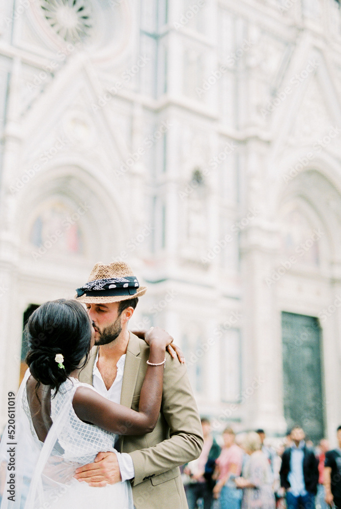 Groom kisses bride in the square in front of the Cathedral of Santa Maria Fiore. Florence, Italy