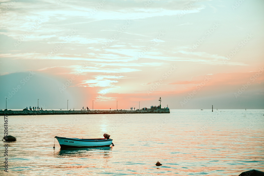 Naklejka premium Boat in the sea against the backdrop of a pink sunset. Leisure a