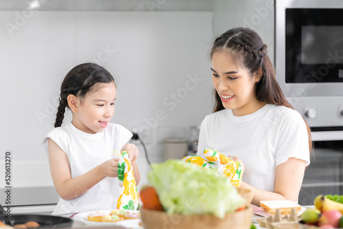 Asian girl learning to cook with mom Do activities together with your family in a fun and joyful way. There is a mother taking care of them closely.