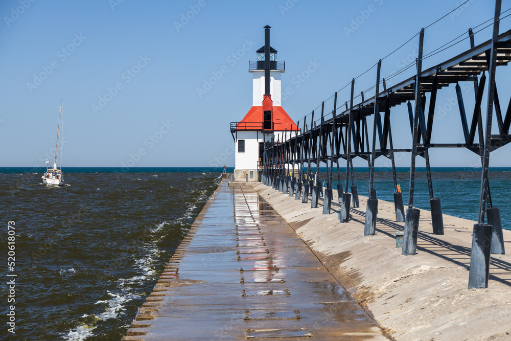 Sailboat going out the channel at St. Joseph North Pier Lighthouse, Michigan