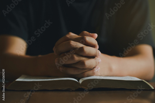 Hand of man while praying for the Christian religion, Man praying with his hands together with Bible on a wooden table Fototapet